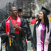 Two students walking in cap and gown